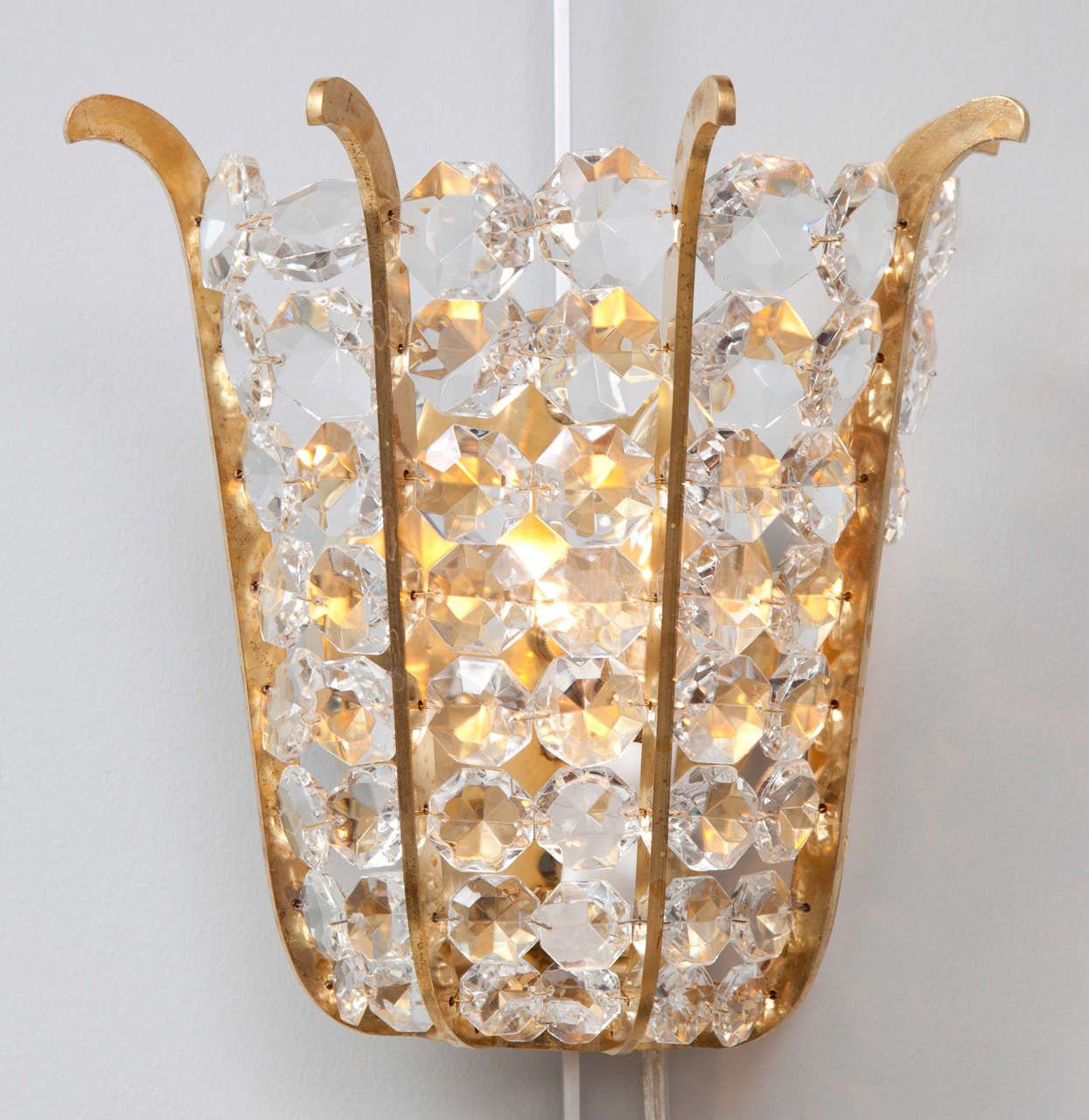 A pair of adorable sconces made up of a brass, tulip shaped frame and faceted crystal beads. These little jewels would be perfect in a powder room or on either side of a mirror. They have been newly re-wired for use in the US.