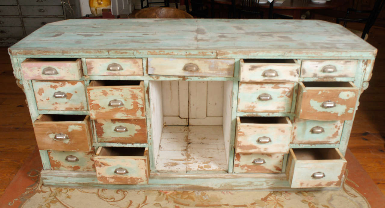 This is a beauty! With totally original and worn paint , this pale shade of green is breathtaking! There are corbels around one side of this counter and 17 drawers on the other side. This makes for an incredibly useful center island for a kitchen.