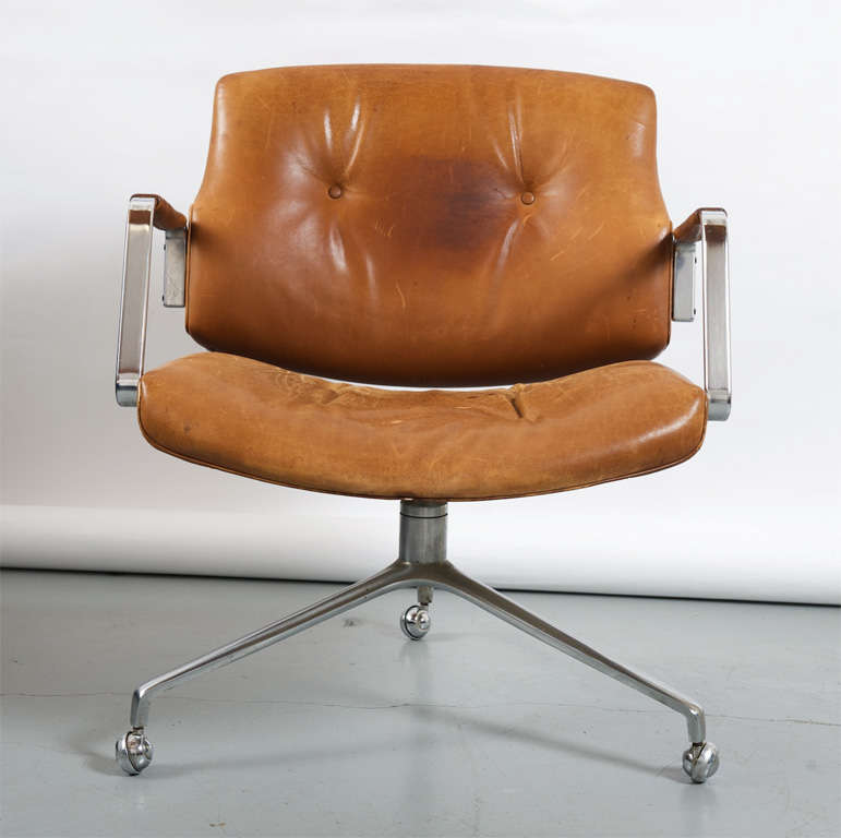 Lounge chair. Seat, back and armrests upholstered in buttoned cognac leather, patina to the leather, matte chromed steel three-star foot, on castors. Produced by Kill International.