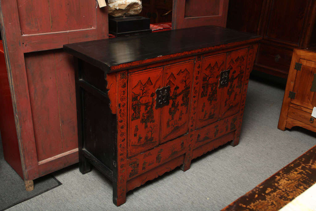 A Chinese red and black lacquered sideboard with gold chinoiserie patterns from the late 19th century. This Chinese 19th Century lacquered wood sideboard showcases typical gold Chinoiserie patterns. The buffet features four doors opening to reveal