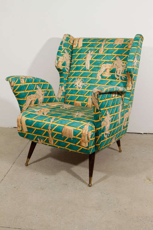 Exceptional pair of club chairs upholstered in an iconic Fornasetti Roman patterned silk. Legs are conical walnut with brass sabots.