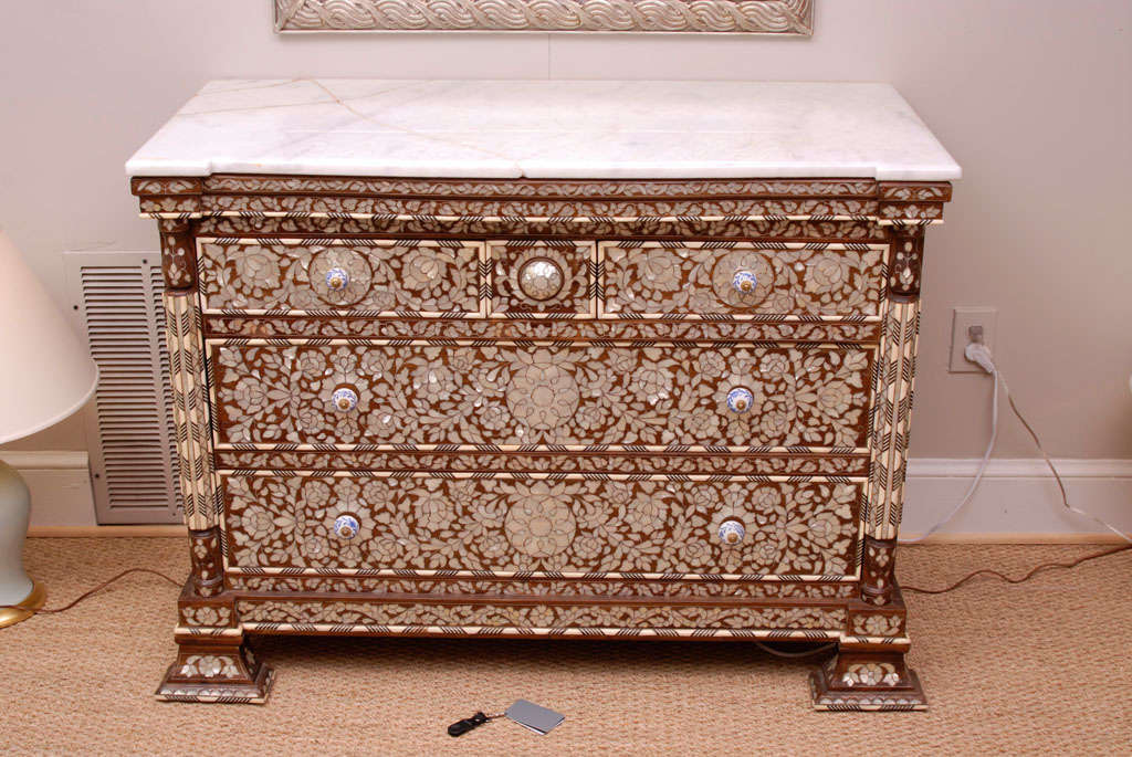 A large and low-slung, intricately inlaid Syrian commode with original marble top featuring two small top drawers over two large lower drawers accented with blue and white porcelain pulls
The extensive inlay is done in a combination of bone, ebony
