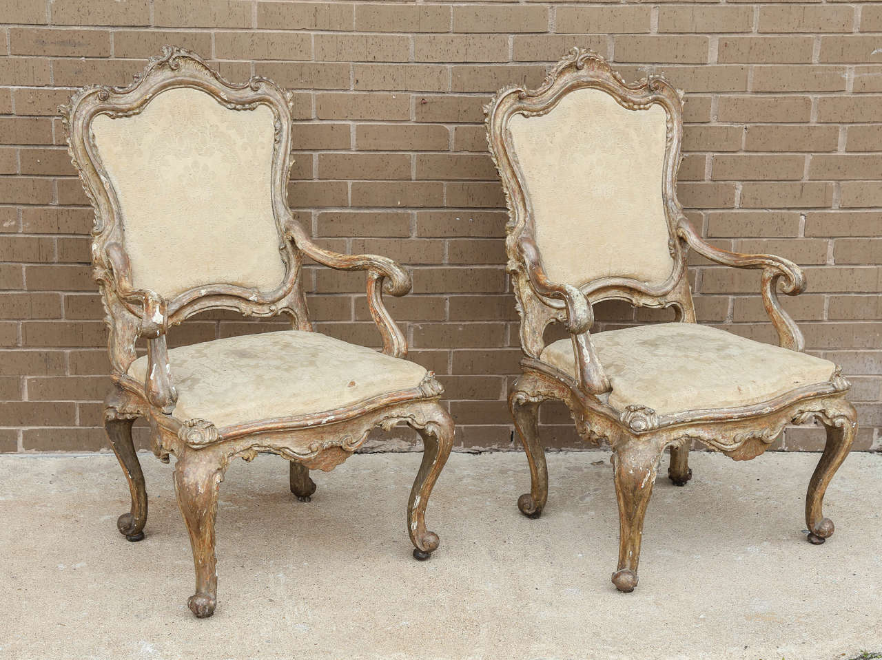Wood carved armchairs from Napes, Italy, circa 1680. Very rare and has the antique fabric in good condition. Some parts appear gold leaf and others look silver.