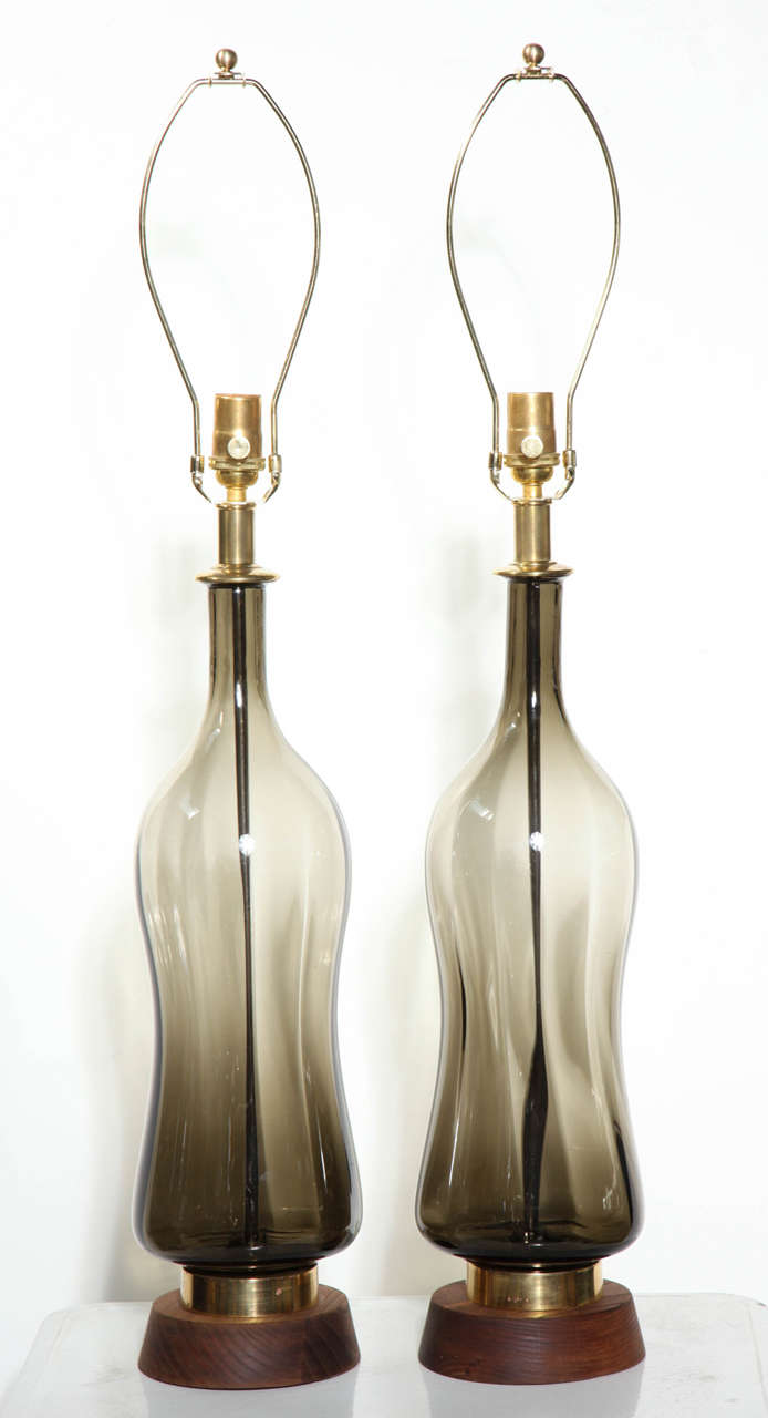 Tall Pair of Smoky Artichoke toned translucent Glass Table Lamps attributed to Blenko Glass Co. Featuring a hand sculpted hourglass forms with gradated smoke brown, olive coloration on turned Walnut base, highlighted with Brass neck and ring base
