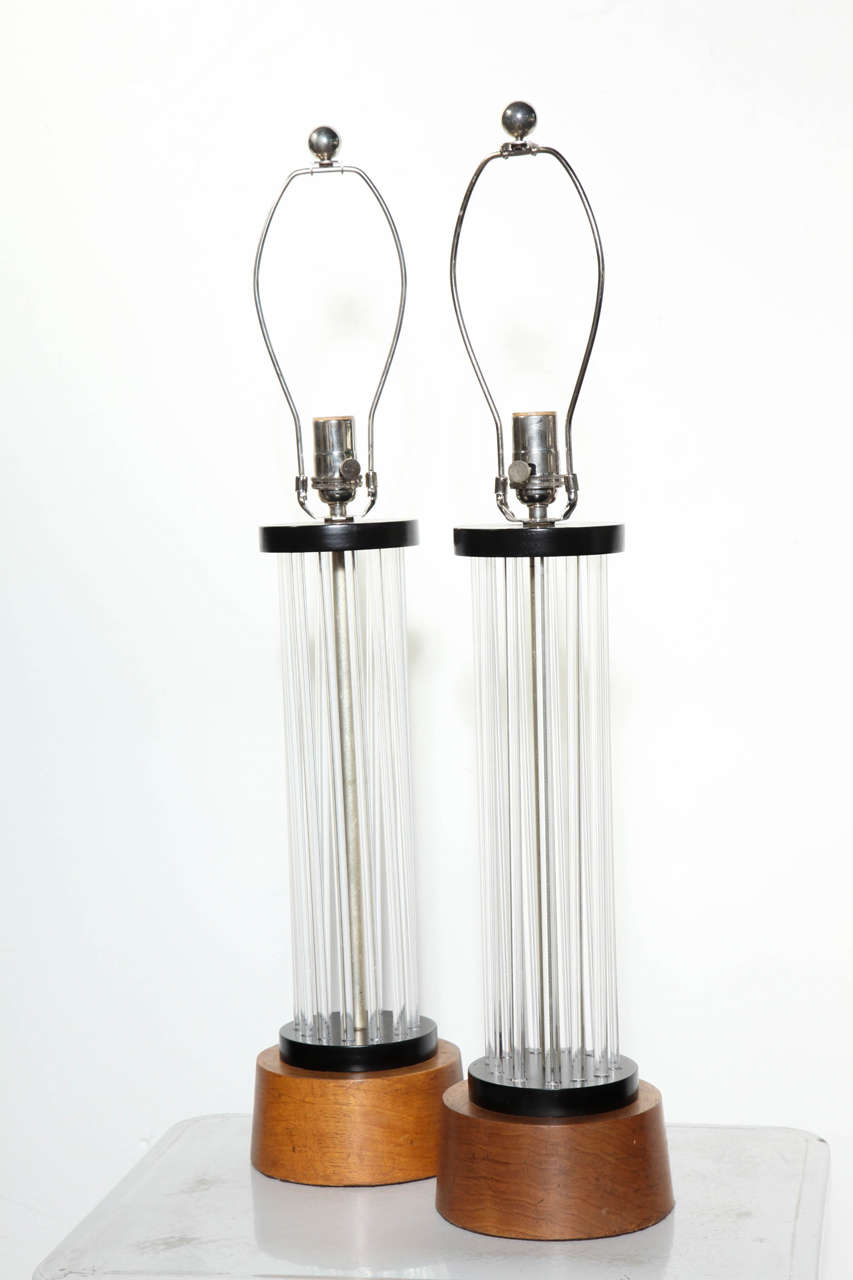 Pair of Hollywood Regency Lucite and Walnut Tower Lamps with Black enamel detail, Circa 1940. Featuring a circular format of 13 clear vertical .5D lucite rods capped with Black enamel discs, atop on tapered (3 H) Walnut bases. Three dimensional.