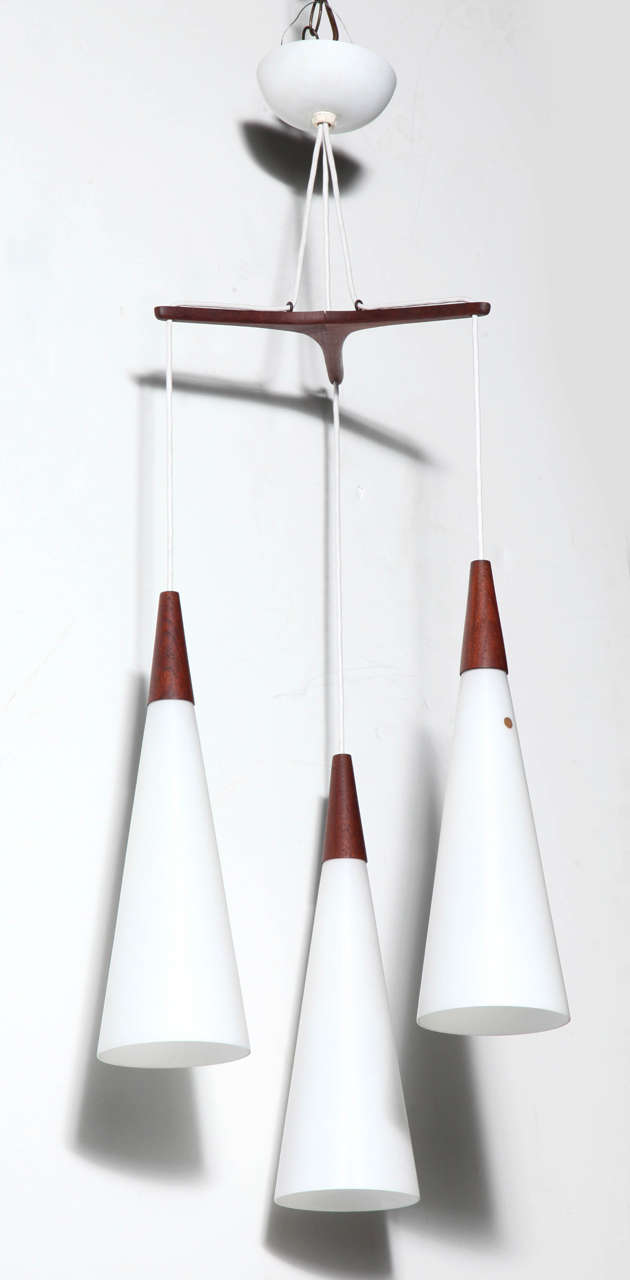 Pair of Holmegaard Denmark Teak Tri Star Triple Translucent White Glass Hanging Lamps. Featuring three-tiered hanging horn shaped White satin opaline cased glass cone shades capped with Teak and suspended from a Tri Star Teak frame. With white cords