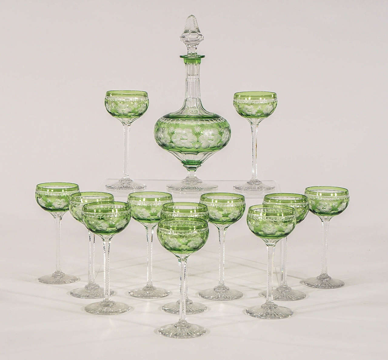 This is a perfect set of 12 handblown crystal cordials cut to clear in an Art Deco inspired floral pattern made by Webb, England. The base is cut with a radiating star pattern and an elegant zipper cut stem. Standing 5 1/4" tall, these are a