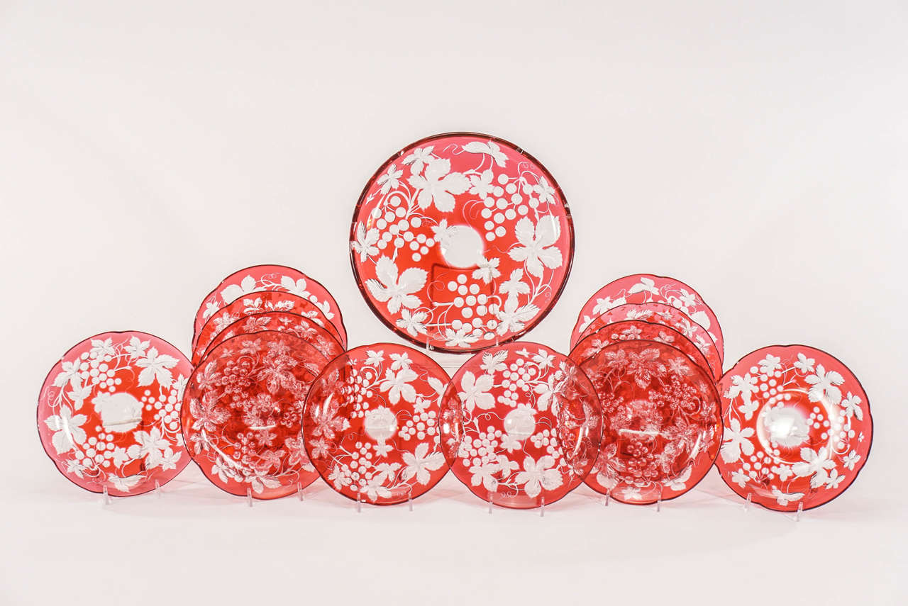 This is a magnificent 19th century set of dessert plates and matching serving plate made by Baccarat. The handblown crystal is cased in a rich and vibrant cranberry overlay and cut to clear in a leaf and grape pattern. The intaglio cutting is