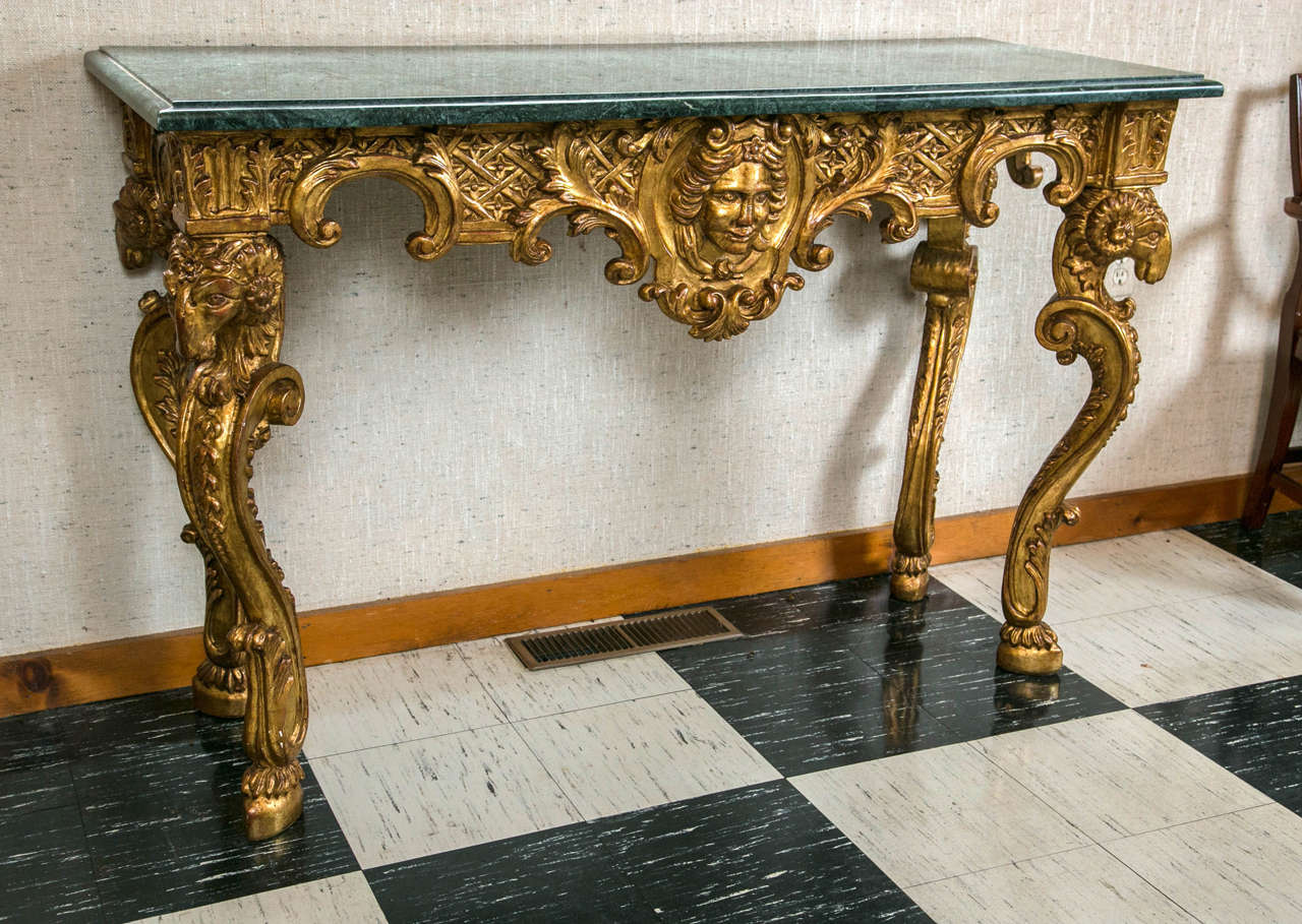 Ram’s head carvings at each corner and a central mask carving are right out of the 18th century neoclassic design playbook. Gilded in a soft gold and wearing a green marble slab, this console has just the right proportions to be a statement piece in