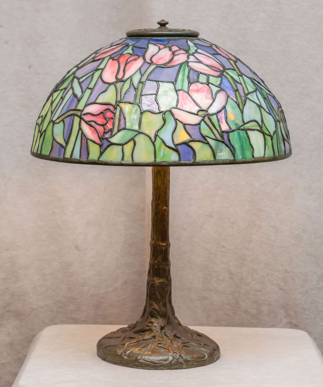 A very colorful and desirable example of an original Tiffany. Both shade and base are properly signed. The shade has some wonderful colors as any eye can see. The bronze base is the tree trunk style and one Of Tiffany Studios most exotic and