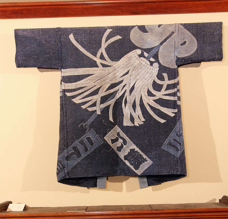 Japanese reversible fireman's coat (haten) of indigo dyed cotton with tsutsu-gaki (wax resist) and painted decoration. The exterior with chidori (plover) and wave motif, the interior with large matoi (fire banner), used to mark a nearby fire and