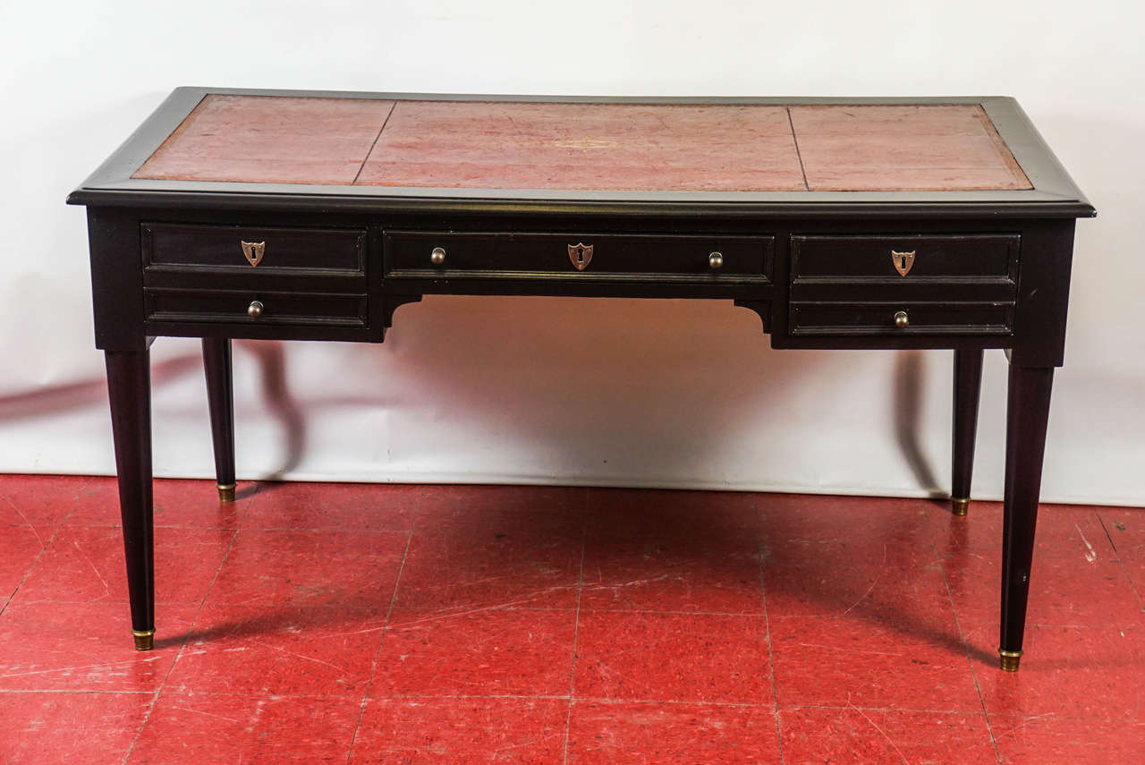 This Directoire/Napoleon III style desk is composed of one large center and two side dovetailed drawers. The right drawer has a divided back section with an inset tray and a horizontal panel that slides over the top of the section to lock (no key).