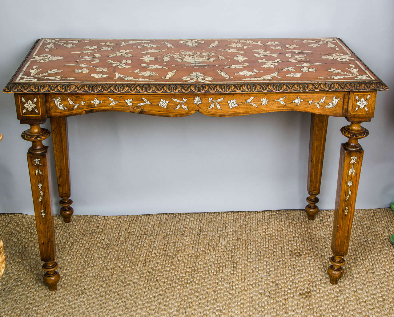 A splendid Italian Inlaid walnut centre table on inlaid tapering square legs. The intricate marquetry work showing floral trails and scrolling foliage centred with a spectacularly beautiful Satyr handled urn from which flowers emerge. The outer edge