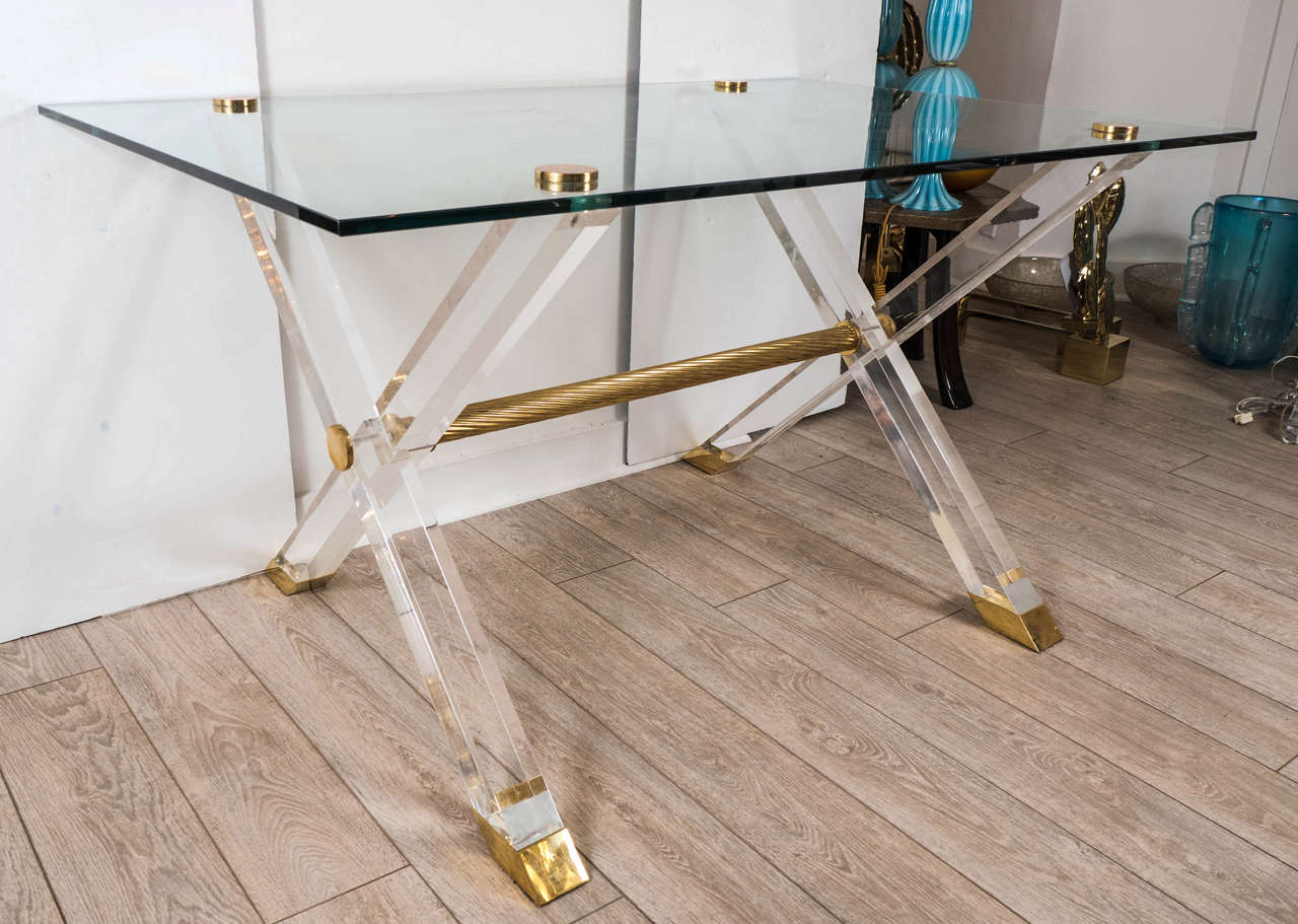 Rectangular desk with lucite cross bar base, brass details, and glass top.
