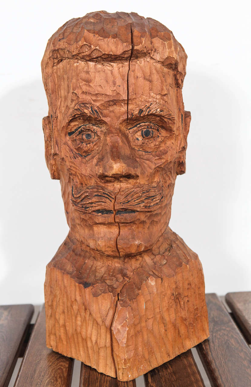 Rustic hand carved bust of mustachioed man.