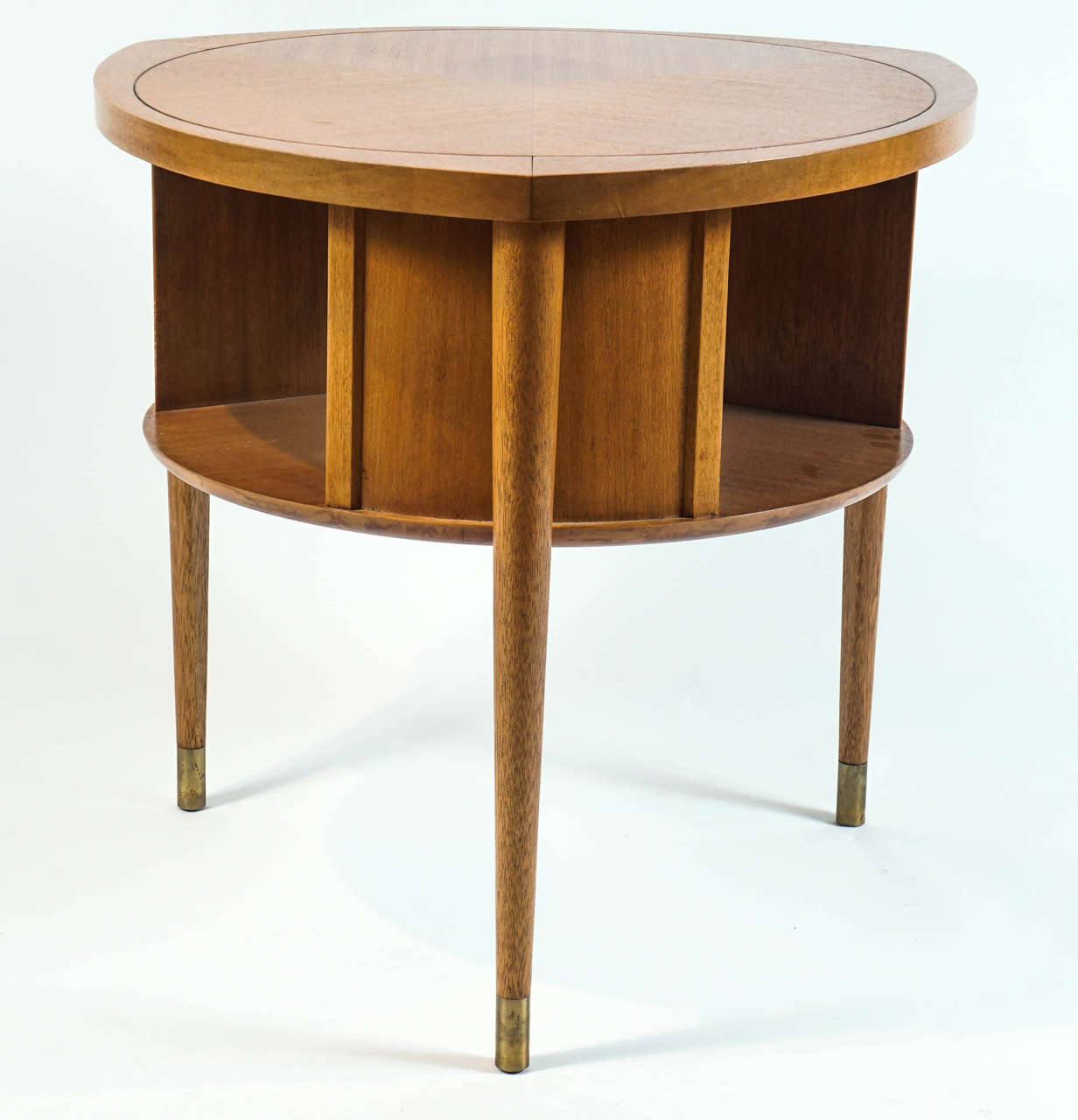 A tricorn-shaped piecrust veneered top atop a circular rotating book shelf that sits on tapered legs with brushed brass sabots. Marked 