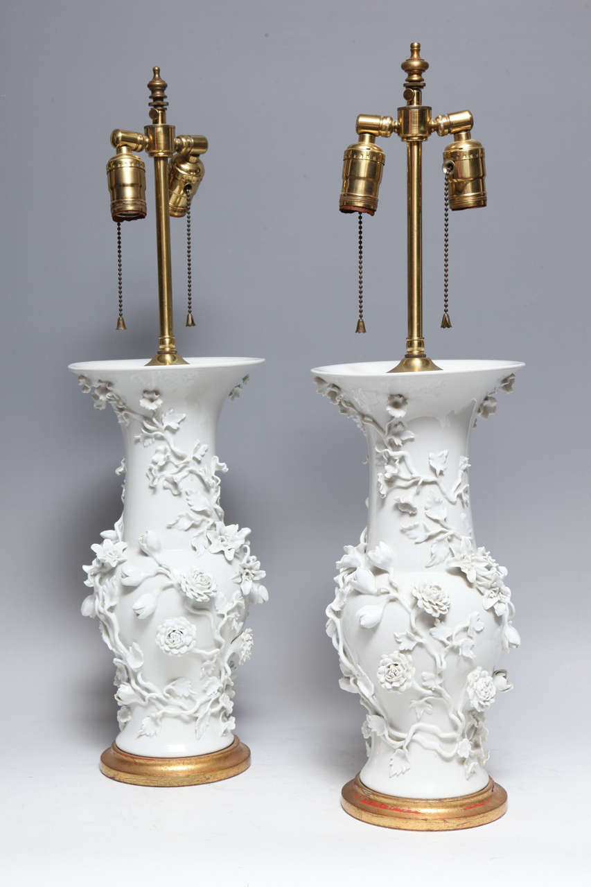 A pair of unusual antique French Louis XVI style gilt mounted white floral paris porcelain vases embellished with three dimensional porcelain flowers in relief mounted on gilt bases as lamps,early 1900's.