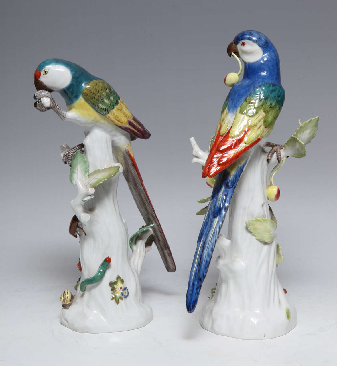 Paire de sculptures anciennes en porcelaine fine allemande représentant des perroquets peints à la main avec des émaux polychromes sur des souches d'arbres:: 19e siècle
