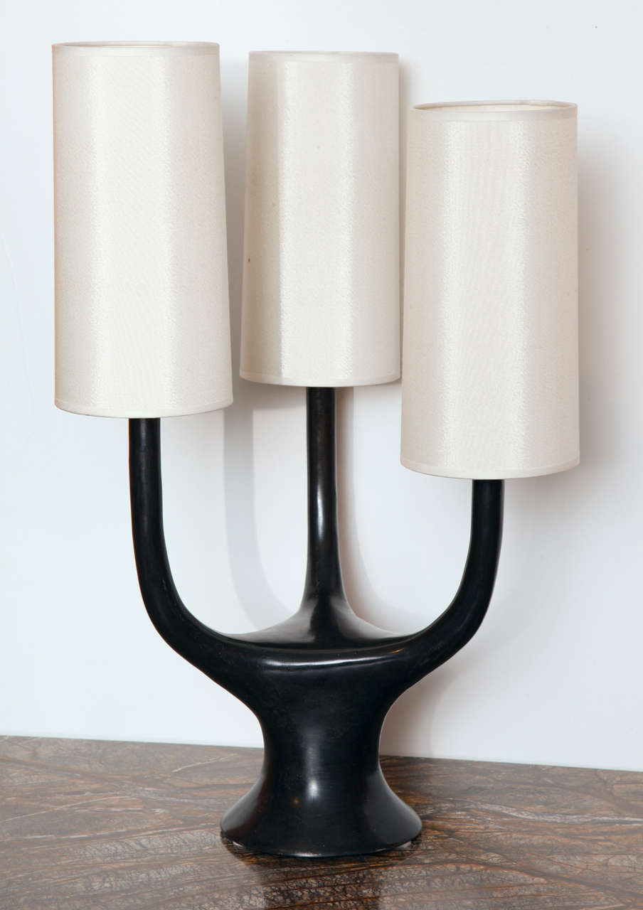 Handmade bronze table lamp with polished finish. Three free-form arms, each holding one candelabra socket and a silk shade. Each lamp is signed at the base. Lead time: 20-24 weeks.
 