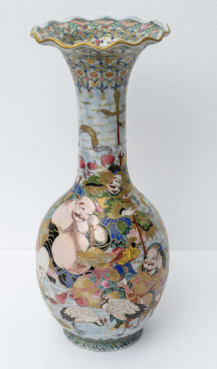 The vase has an elaborate design or scene that is continuous around the vase. The vase starts with a scene that has a woman and two men sitting around a plate with a fish on a plate. Behind them is a spotted deer looking up towards the sky. There