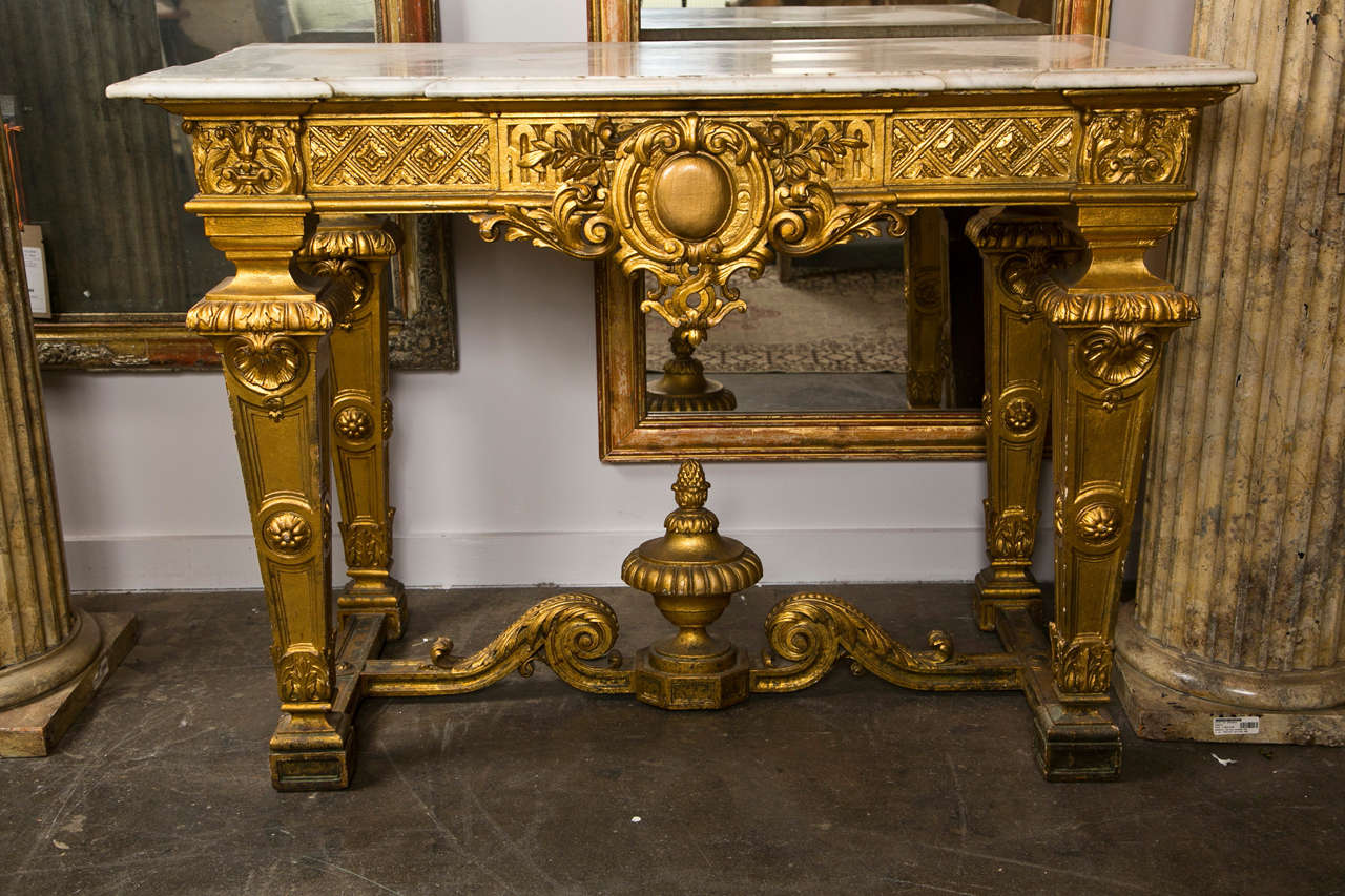 French gilt wood console, c.1880- 1900, in the Louis XIV baroque style with shaped carrera marble top. From a Westchester estate.