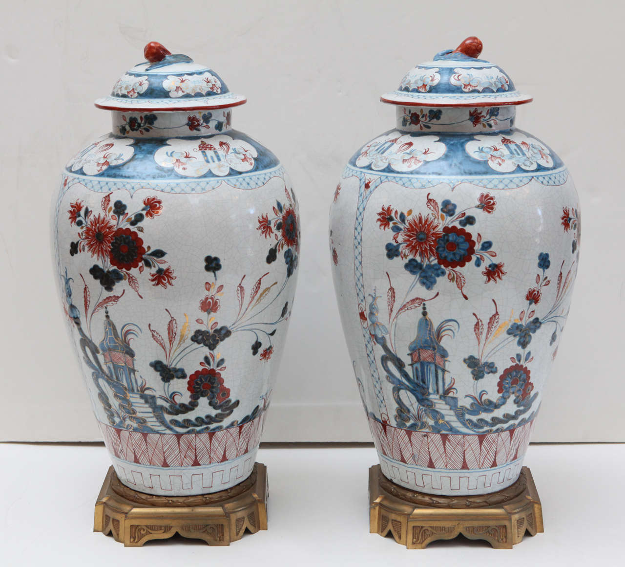 A pair of left and right, lidded, Venetian-style, parcel gilt, Delft urns mounted on gilt bronze bases.