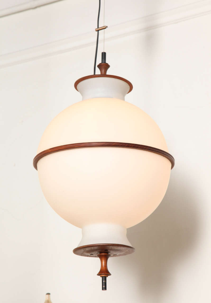 Stylish pendant light fixture mad in Milan in 1955, very unusual model. White double blown milk glass shades with mahogany and patinated brass mounts hanging from a cable wire, great design and form of beautiful quality. You can make it any length