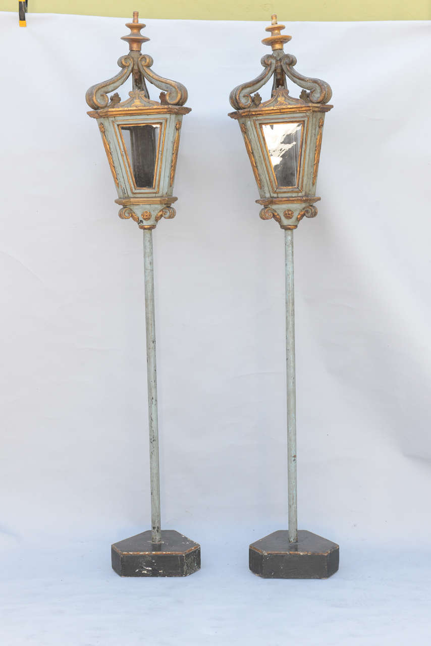 Rare pair of fabulous lanterns, painted and parcel gilt, each light having three framed glass inserts surmounted by elaborately carved scrolls; originally lights on Venetian gondolas, now purposed as floor lamps; not electrified.
