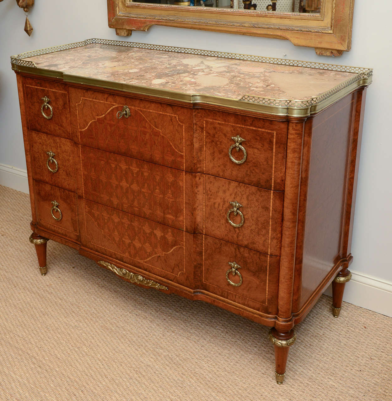 Secretaire, having notched marble top with 3/4 pierced bronze gallery, the top drawer opens to a writing surface and inside, an arrangement of pigeon holes and two central drawers; the case, of burlwood, has stringing and beautifully inlaid designs
