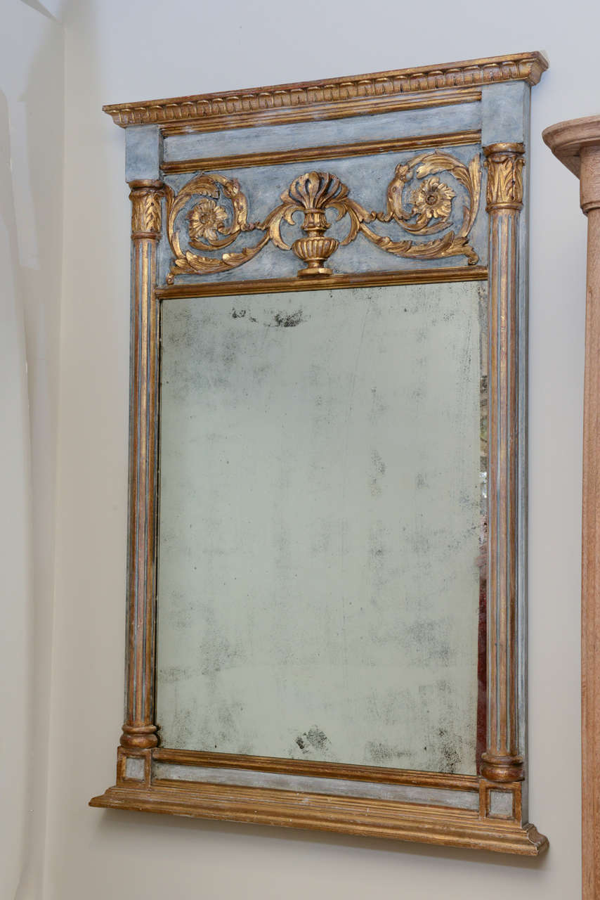 Pair of mirrors, in classical form, painted and parcel gilt, each having a rectangular mirror plate surmounted by gadrooned frame and outcarved gilded panel centered with urn flanked by scrolling floral motifs and fluted stiles with acanthus