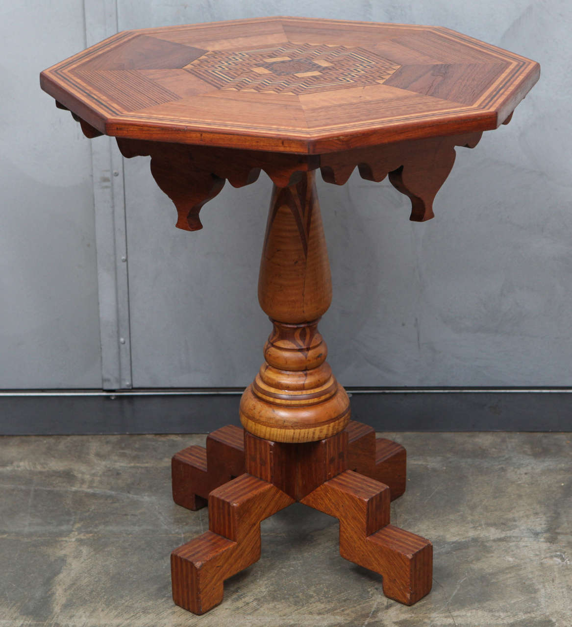 This eight sided American folk art table has great parquetry details in an impressive geometric pattern and inlay work that is used throughout. The table stands on a center column is turned with inlay details which create beautiful graceful lines