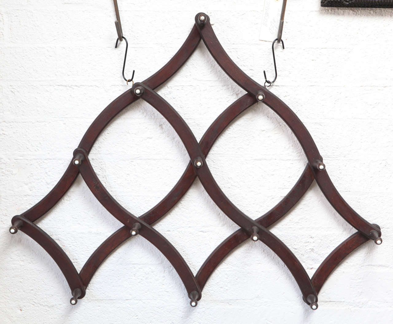 This is a handsome folding hat rack that can be hung horizontally or vertically for a variety of lovely shapes. This is a solid American piece of workmanship circa 1880 having 14 turned wood pegs with porcelain buttons. The measurements for the