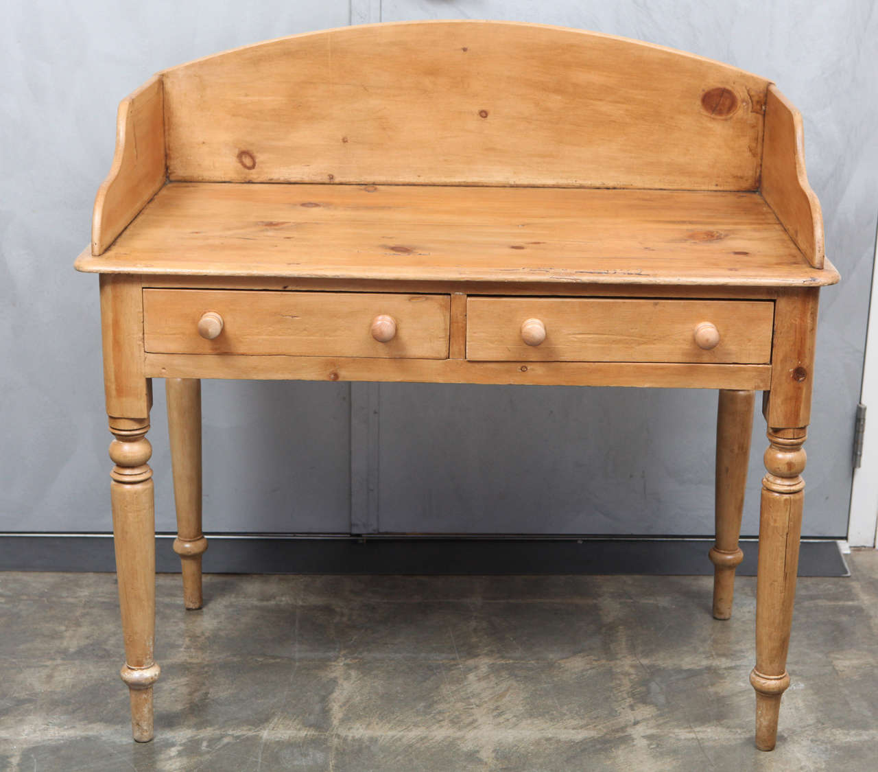 This English pine wash stand with side and back splash boards has a modern use as a desk or writing table. This piece displays remarkable construction which tells the story of a hardworking piece of furniture. The desk has some distressing in the