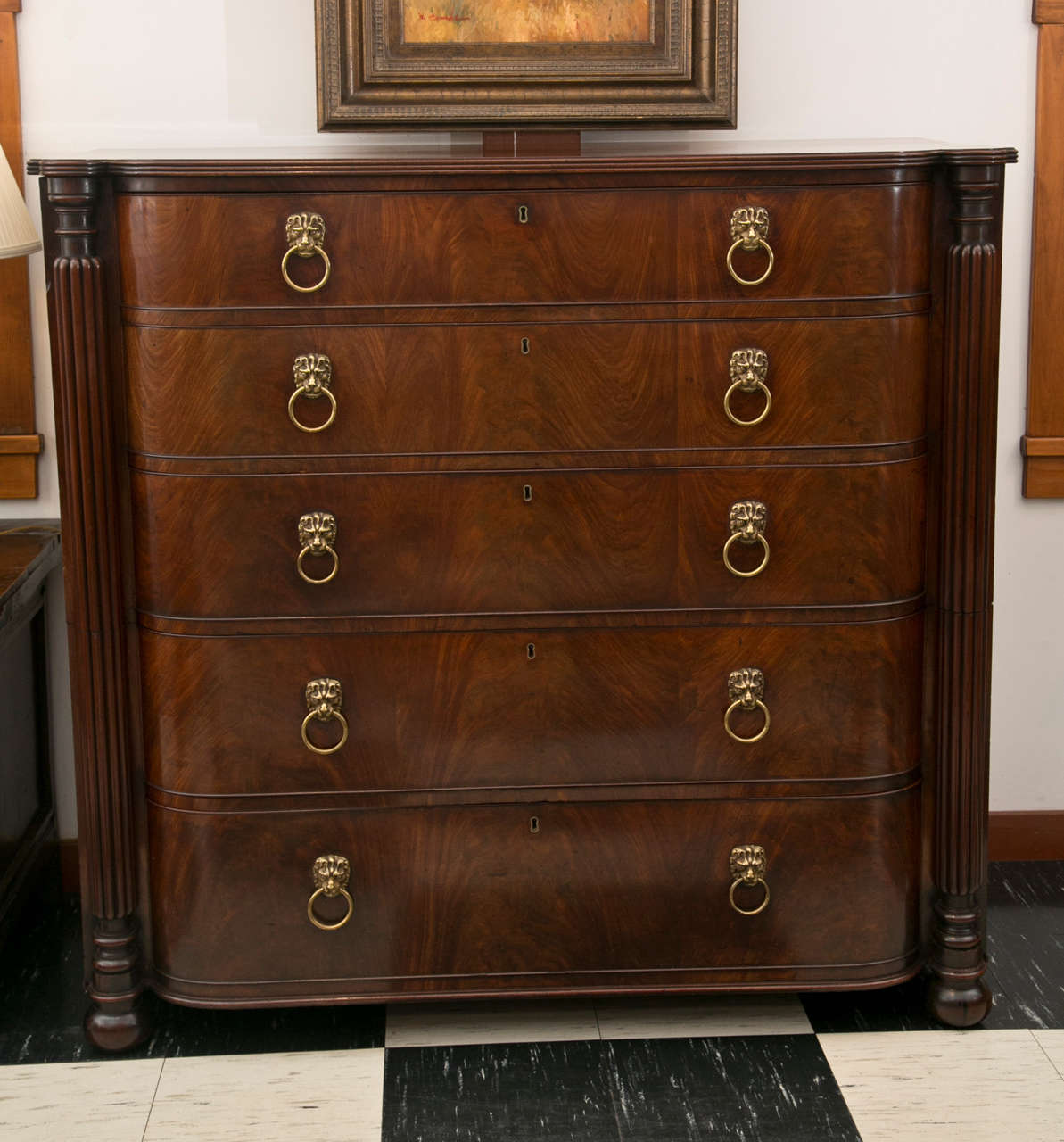 This handsome Regency chest in two parts has five long, graduated drawers with brass lion’s mask ring pulls and a grain pattern that virtually flows across the surface. All of this is effectively framed by reeded pilasters that terminate in turnings