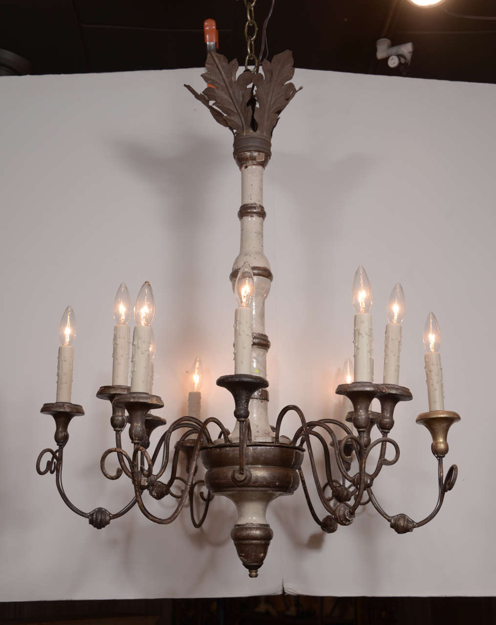 19th century Italian chandeliers consisting of ivory painted turned wooden bodies, silver-leafed iron arms and tole acanthus leaf crown. Newly-wired for use within the USA with twelve lights each. Chandeliers include extra chain, canopies and