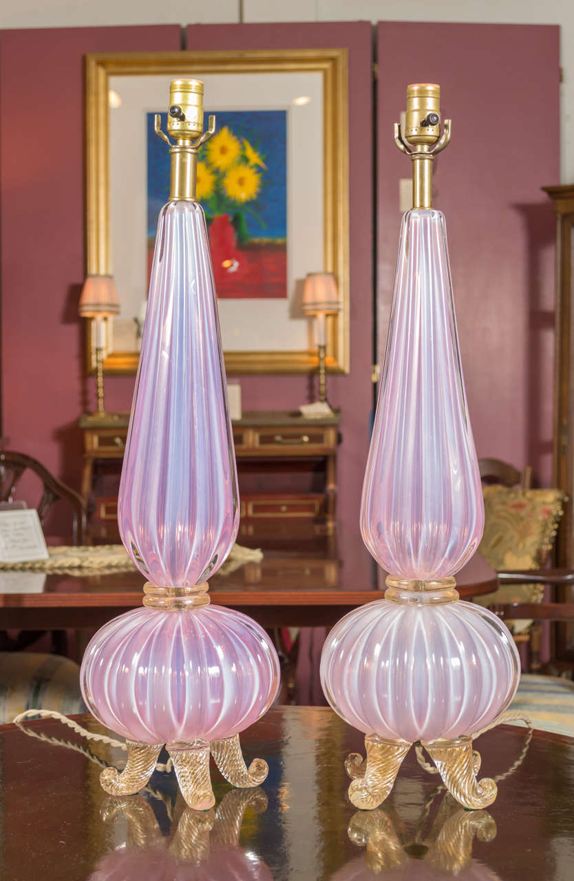 Offering a pair of 1950's/ 60's Italian hand blown glass lamps by Seguso,.  The lamp features deep vertical ribbing.  The sommerso lamps are pink opaline under clear glass.  The tripod feet are clear containing gold leaf inclusions.