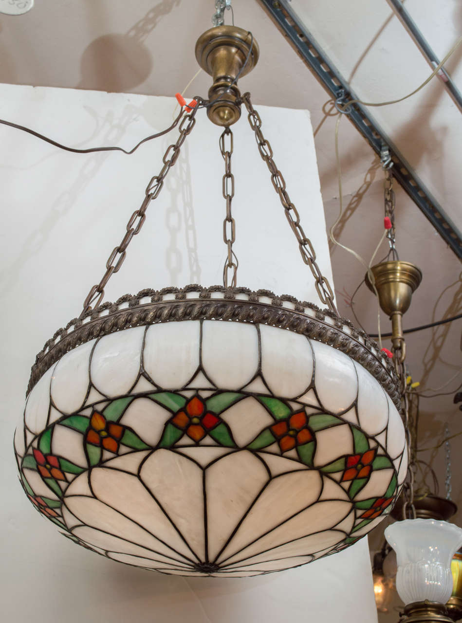 We are always being asked for leaded glass pendants that when looking up, you do not see the exposed glaring light bulbs. Here is a very nice example of that. Besides the colorful flowers, there is nice patinated brass trim together with the