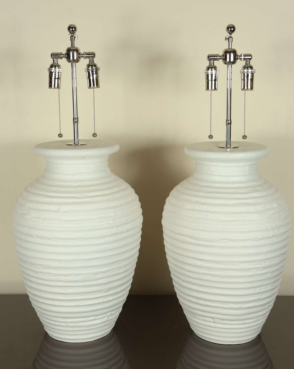 Pair of lovely urn shaped table lamps in white matte finished ceramic.   The bands show the potter's touch.   They have been rewired and outfitted with nickel double clusters.