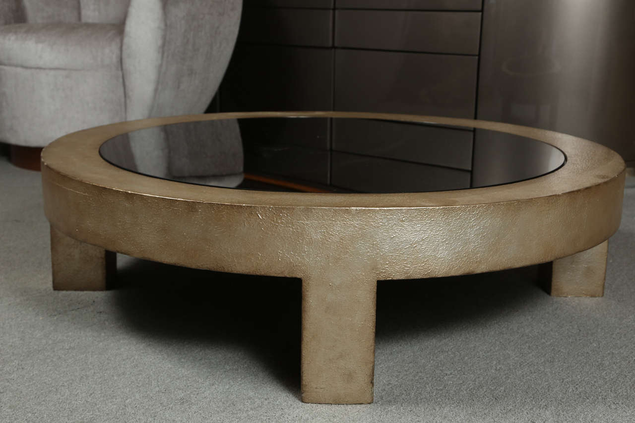 Beautiful low coffee table by James Mont.  The wooden frame has a textured gesso surface finished in a dull silver /  gold leaf finish.   The central surface is antiqued gray mirror. The table is also branded James Mont design on the underside.