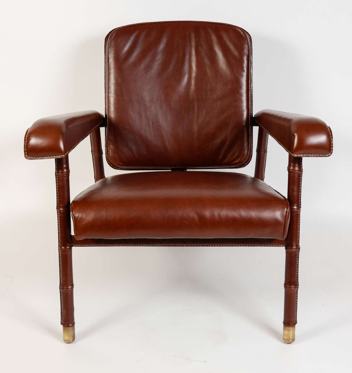 1950s armchairs in brown stitched leather designed by Jacques Adnet.