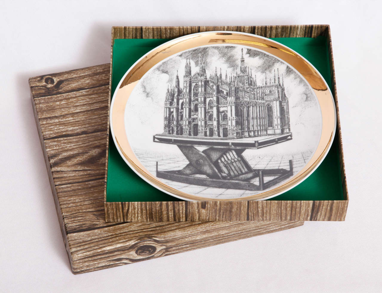 A limited edition porcelain plate showing the Milan cathedrale (Italy) designed and executed by Piero Fornasetti (1913-1988) with its original wood-like box.