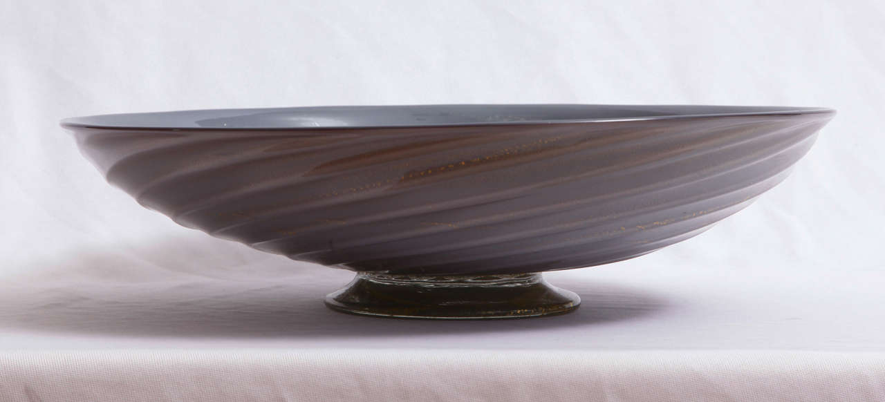 Rare glass bowl on foot with twisted ribbed surface designed by the Italian glass designer Flavio Poli (1900-1984) and executed by Barovier Seguso Ferro (former name of Seguso Vetri D'Arte, Murano until 1937). The 'Grigio oro' series was introduced