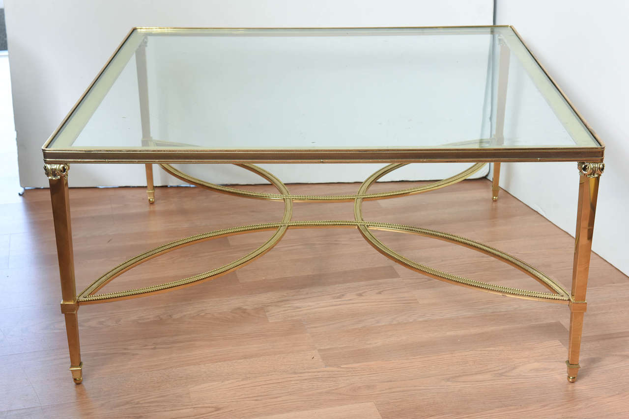 Glamorous solid brass coffee table with beaded swirled stretchers and glass top set in chased brass gallery.  Attributed to Maison Jansen.