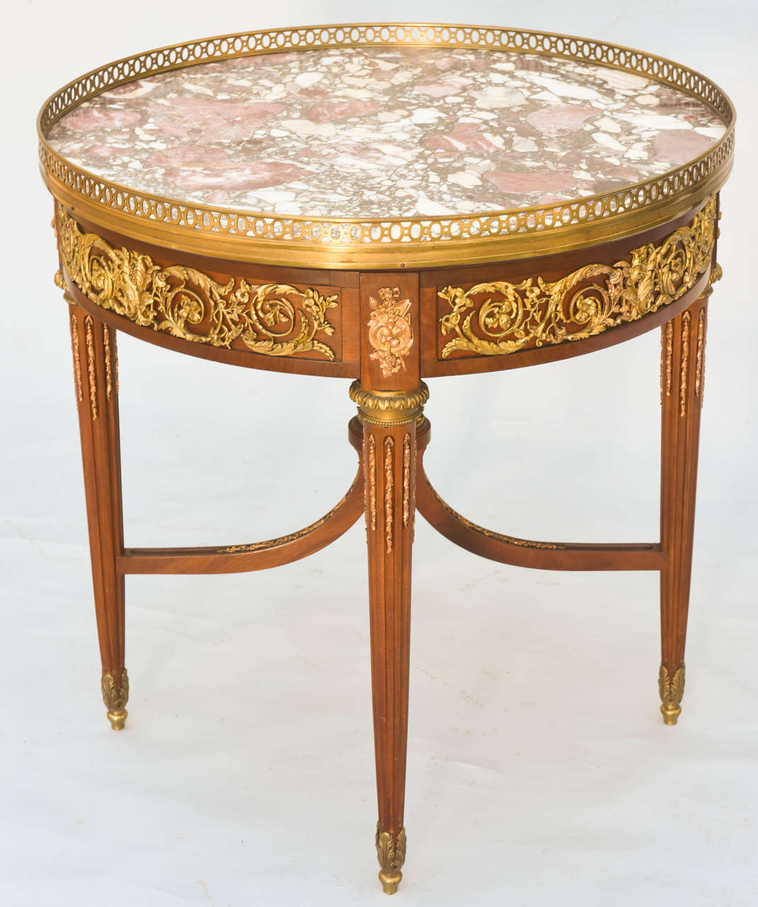 Very fine bouillotte accent table, having breccia rosa marble top with brass gallery, apron with ormolu mounts, raised on fluted legs, connected by dramatic upswept stretcher with acanthus crown.

Stock ID: D9242