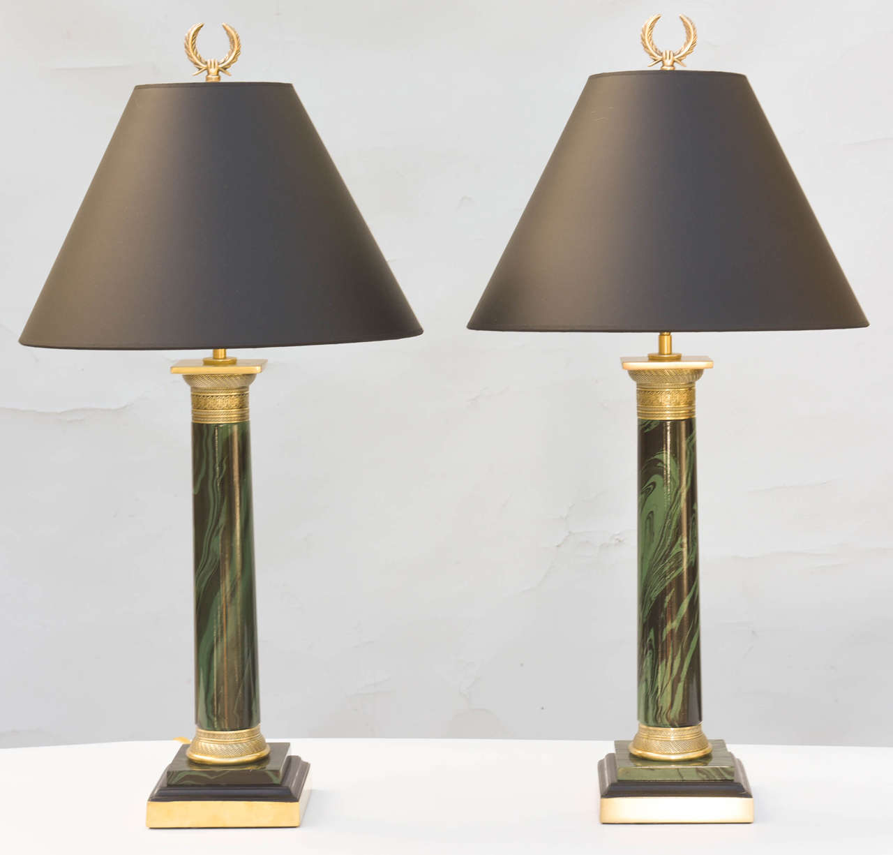 Pair of lamps, of metal, column form, painted in faux malachite, having chased brass capital and collar, on square graduated bases. Shown with black file shades (not included).

Stock ID: D9237