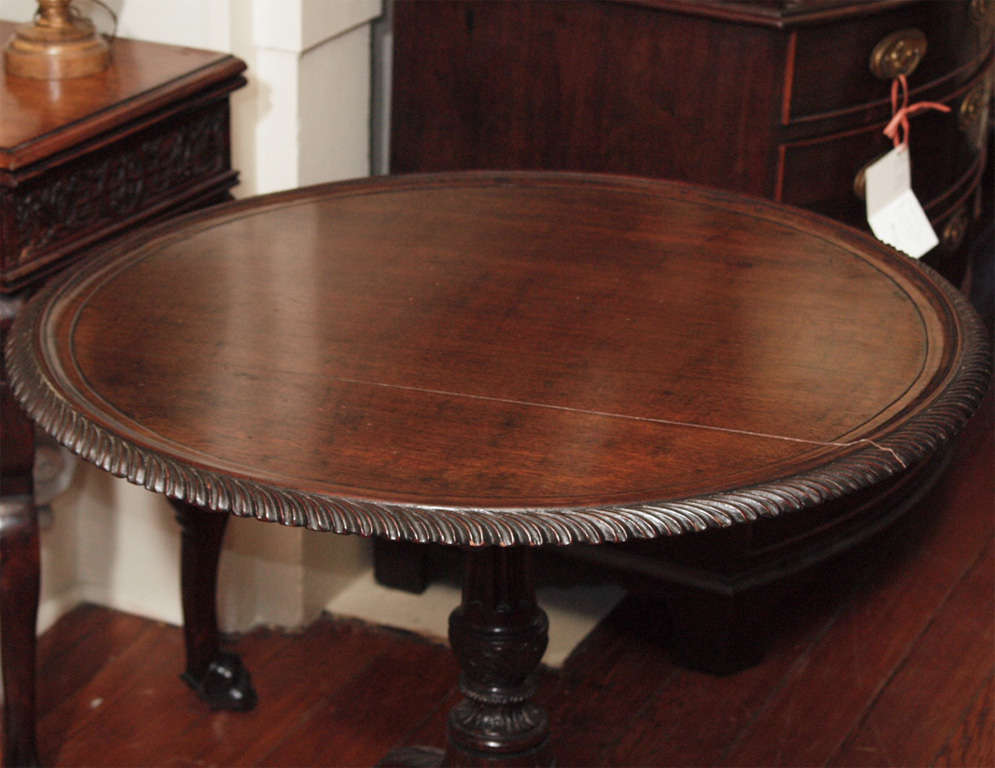 A fine pie crust tilt top table, likely English or Irish, with finely detailed carvings on the top, post and knees of the tripod legs.  The center post is fluted with a figured vase, the knees with a leaf design, and the top with a finely carved