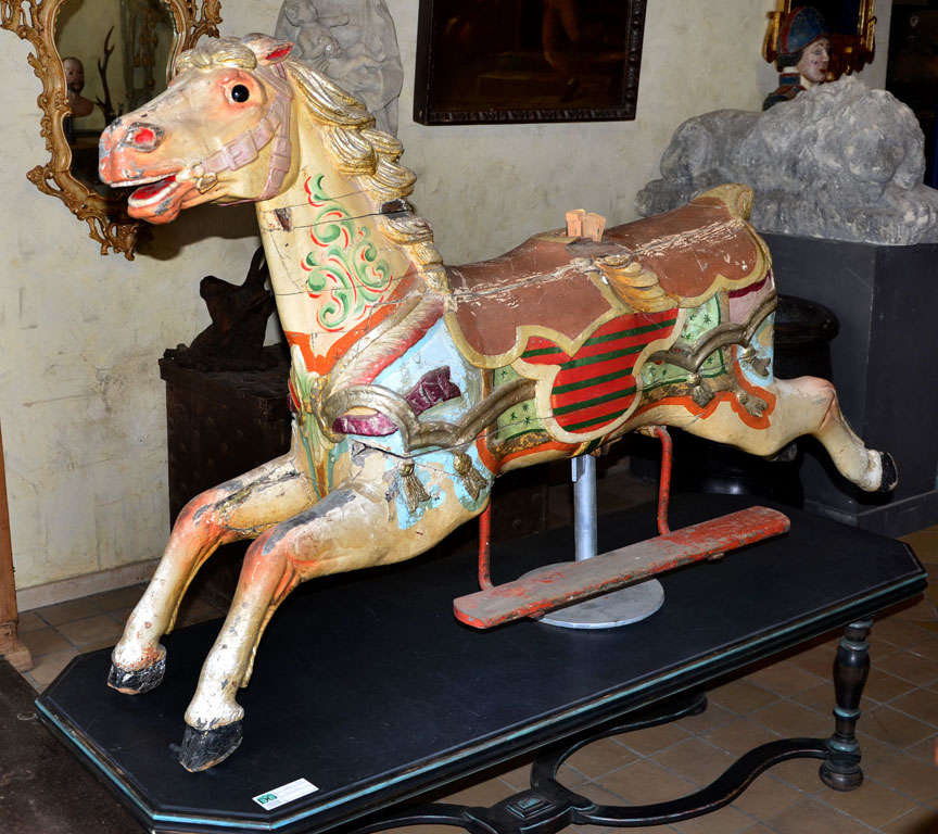 A carved and polychrome painted wood fairground horse, 19th century, naturalisticaly carved in a leaping position, later associated stand, 110cm high, 170 cm long