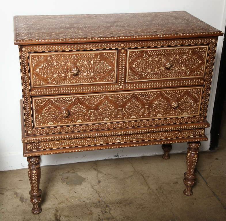 A chest of three drawers on legs from India with bone inlays throughout in an intricate traditional patterns.
