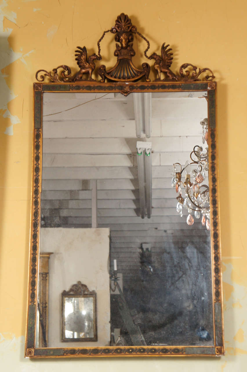 French Empire Style gilt and hand painted mirror with two carved griffin decorations.