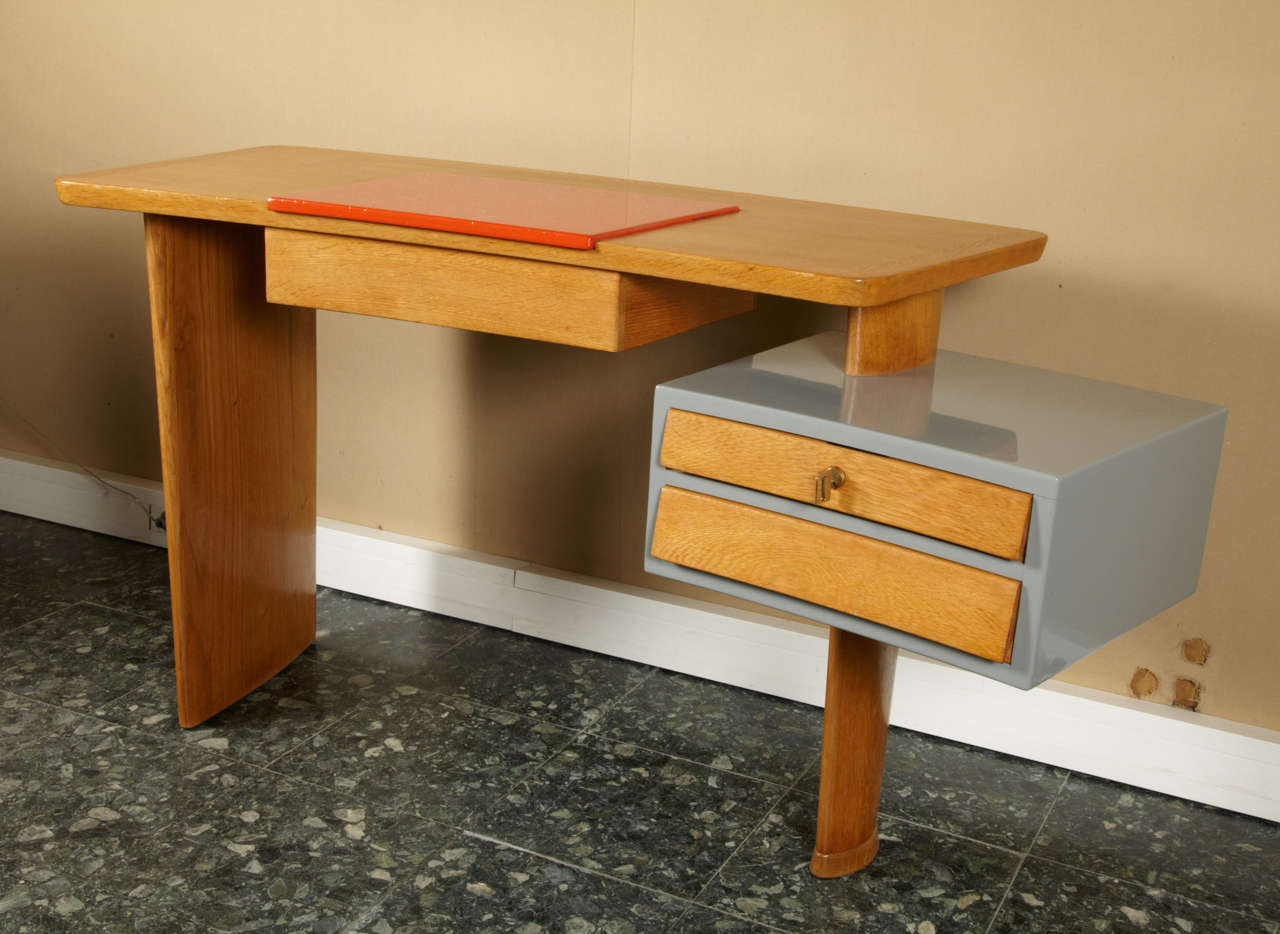 1950s asymmetrical desk by René Gabriel, with the original  gray lacquered chest and two drawers; top surface has the original orange lacquer element which can be raised and has an interior storage area. Legs shaped like the wings of an airplane.